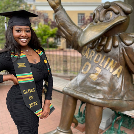 Graduate posing with the Cocky statue.