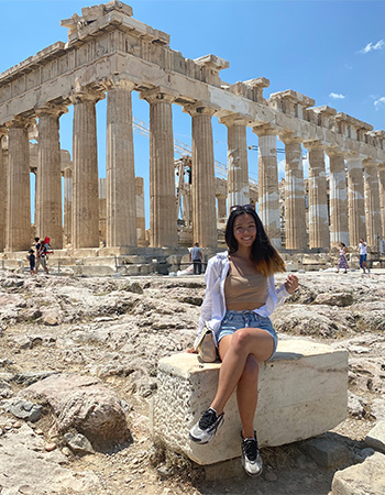 Chelsea Chang sitting in front of ruins on a study abroad trip.
