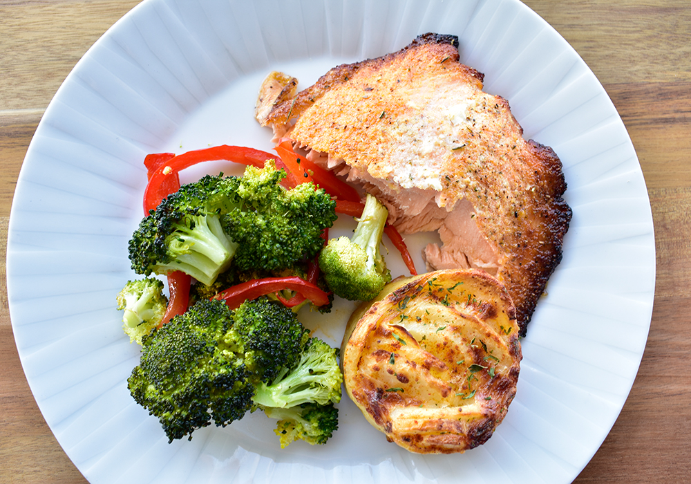 A plate of salmon, broccoli and potatoes.
