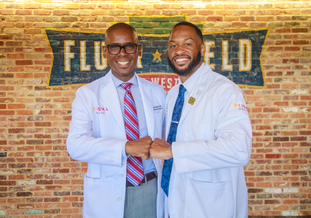 Two male African America students celebrate at the white coat ceremony.
