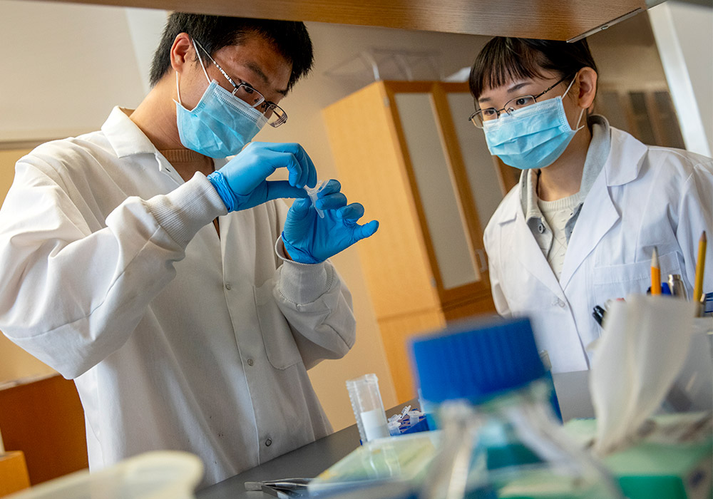 Researchers wearing lab coats working in a lab. 