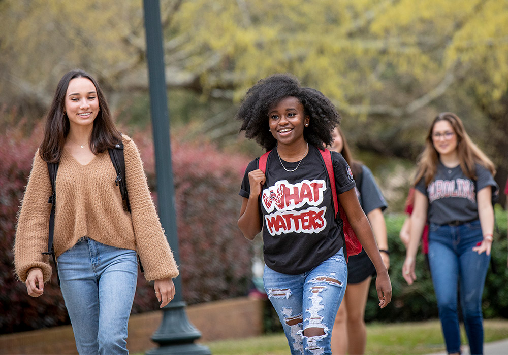 Students smiling as they are walking to class on a beautiful sunny day. 