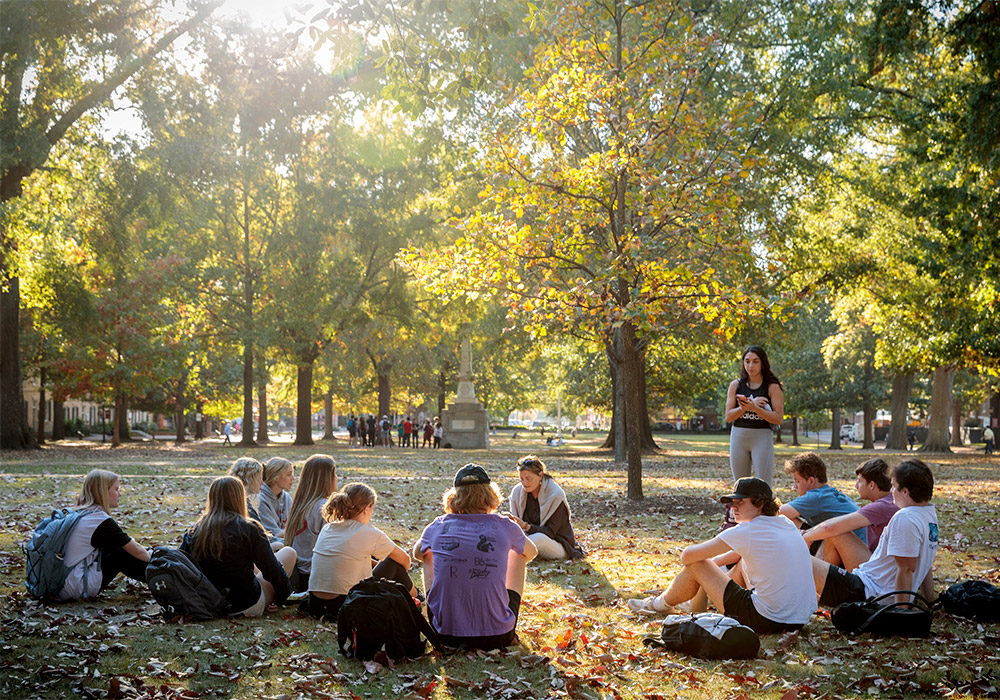 A group of students sitting on the Historic Horseshoe having class outside on a beautiful fall day.