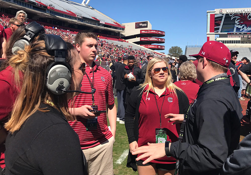 Group of student interns take direction on the the football field at Williams Brice Stadium.