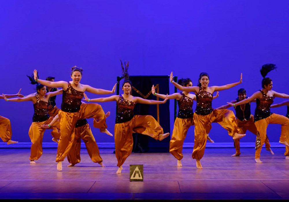Moksha dancers performing in costume on a stage. 