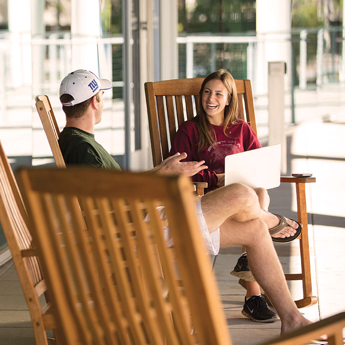 Two students sitting in rocking chairs laughing and smiling. 