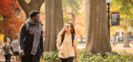 Two students walking down a path on the historic horseshoe on a beautiful fall day.