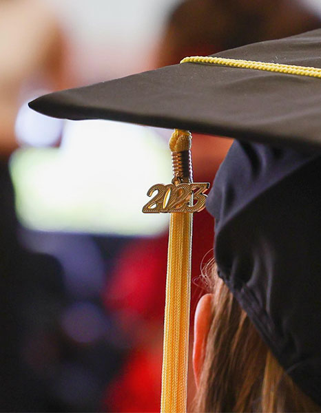 The tassel on a graduation cap with a metal tag reading 2023.