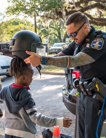 A police officer helps a child put on a helmet