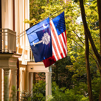 The South Carolina flag, United States of America flag and hanging on the side of the president's house. 