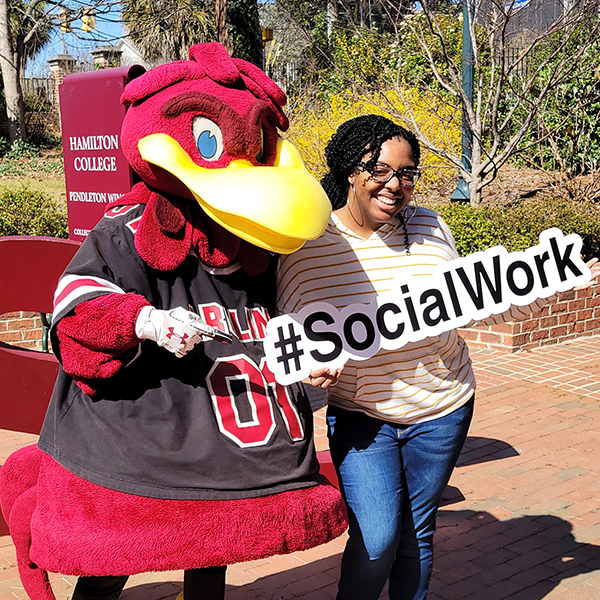 Cocky with a student holding a sign that says #SocialWork.