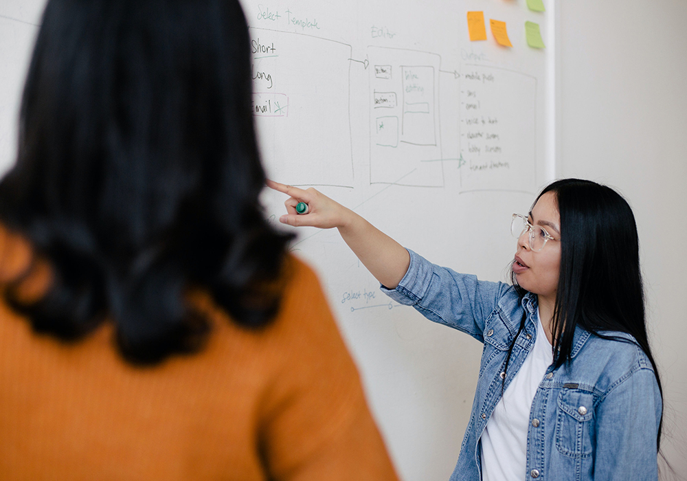 two women working at a whiteboard
