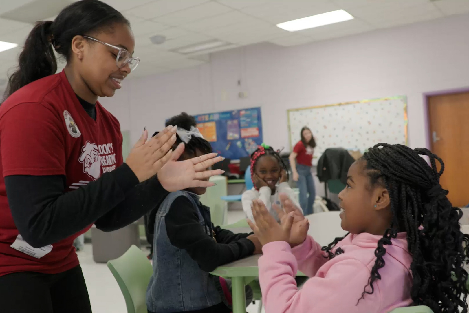A teacher and student play pattycake