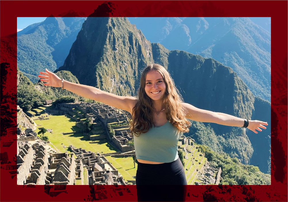 USC alumni Kayla Davenport smiling in front of the stone terraces and green mountains of Machu Picchu on a clear day