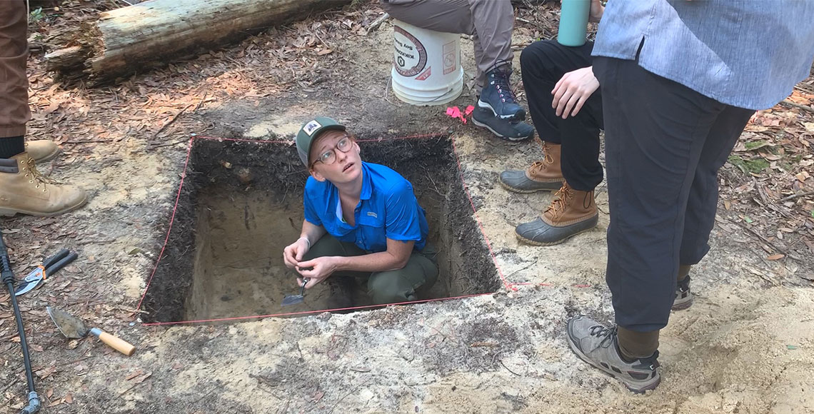 Students digging in a large square hole. 
