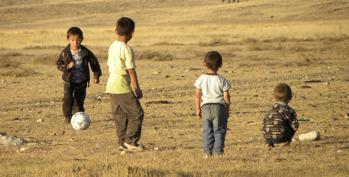 Young children play with a soccer ball in an open field in the village of Koyan, Kazakhstan. Photo by Magdalena Stowkowski
