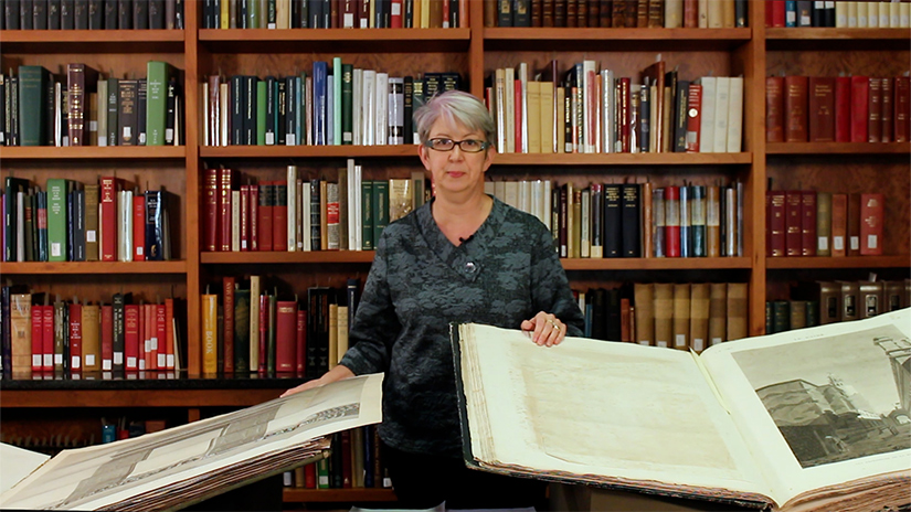 Photo of Carol Harrison with books in a library. 