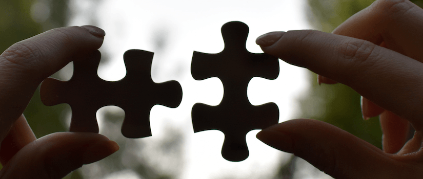 two hands fitting puzzle pieces together