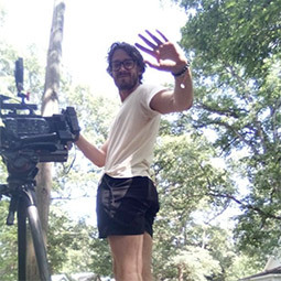 photo of a man waving outside standing behind a camera