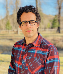 Portrait photo of Berns posing outside in a red flannel shirt and glasses.