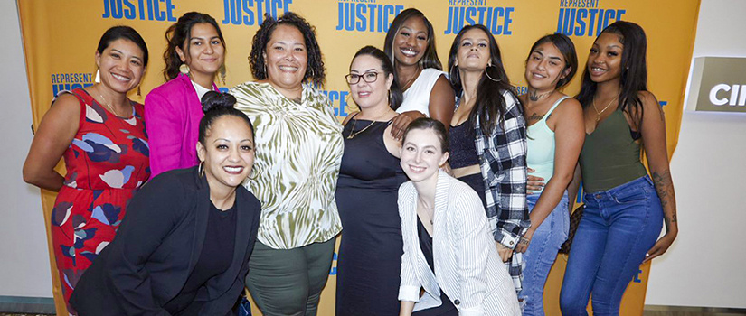 A group of attendees smiling at a film premier for Represent Justice. 