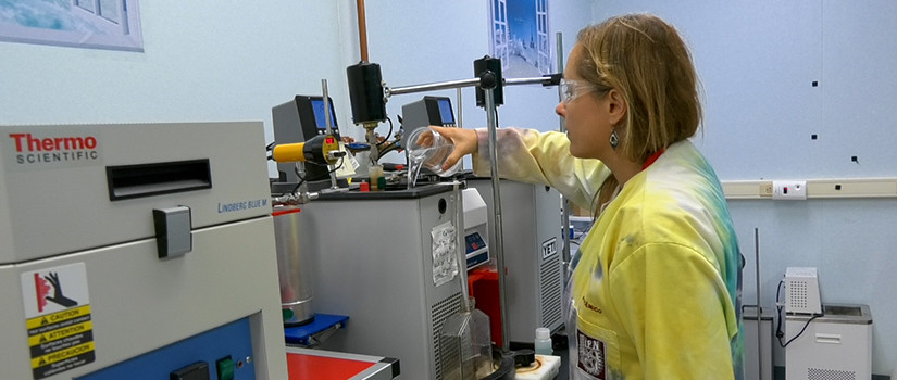 woman in lab coat working in a lab with water samples