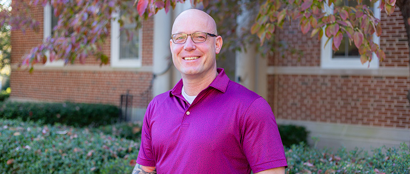 a man standing outside with a bright magenta shirt on