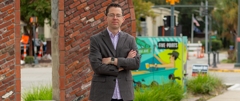 Brian Levy, a USC sociology professor, standing in an urban neighborhood near a mural in Five Points, Columbia, South Carolina.