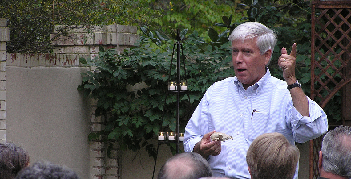 Rudy lectures in a garden during the evening hours. 