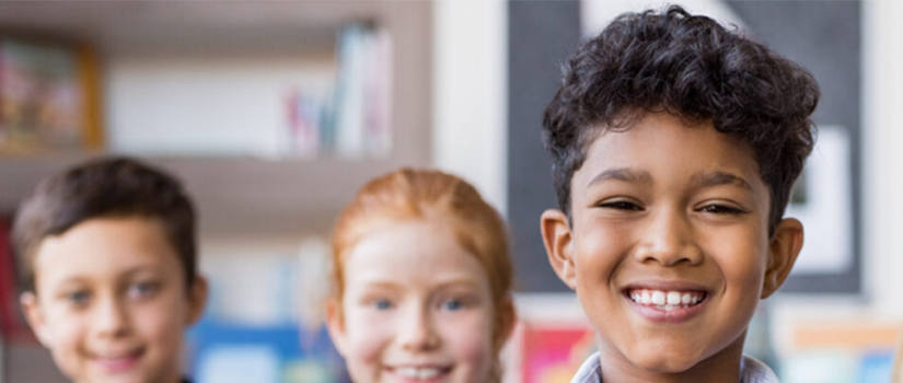 a photo of three children smiling inside a classroom