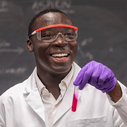 student with goggles on in a chemistry lab working on equipment 