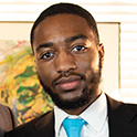 Photo of Jahleel Johnson l German Studies Student in a black suit with a yellow tie.