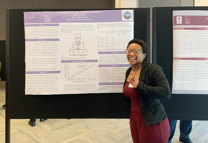 Jasmine Bohannon stands in front of a chemistry research presentation poster