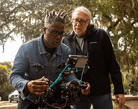 two men working with a camera outside 