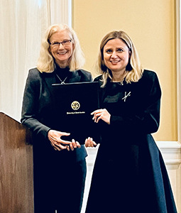 two women dressed in black holding an award