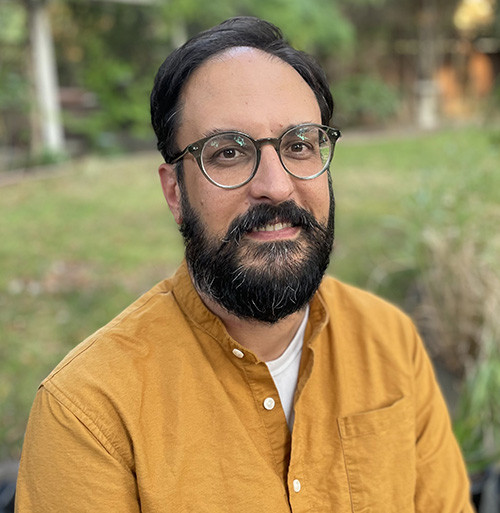 a man with a beard in a mustard yellow shirt