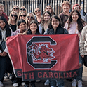 students in UK during maymester holding a Gamecock flag