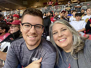 Nick Tice and his parent with people in the background at a game.