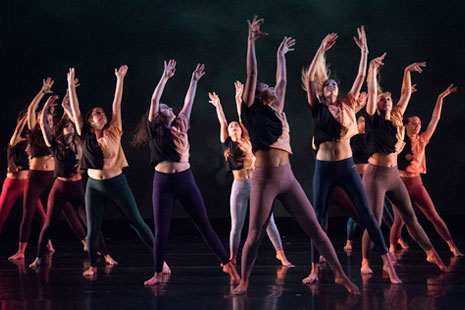 Click to view video.  Shown: Group of dancers with arms raised in Fall 2019 Student Choreography Showcase