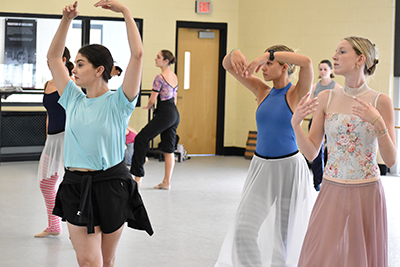 Kathryn Morgan on the left wearing a light blue shirt and black skirt teaching choreography to USC dancers on the right.