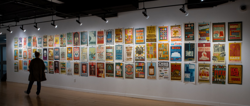 A gallery visitor observes a wall of letterpress poster by Brad Vetter in the "Makeready" exhibition.