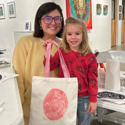 An art education instructor and student pose with a printed canvas tote bag at Stormwater Studios.