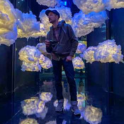 Herman Phillips stands in an art installation filled with fluffy clouds.