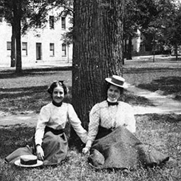 historic image in black and white of two women sitting on the horseshoe