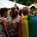 Group of people facing away from the camera. One person has rainbow flag draped over their shoulders.