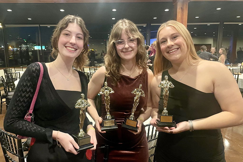 three students holding trophies