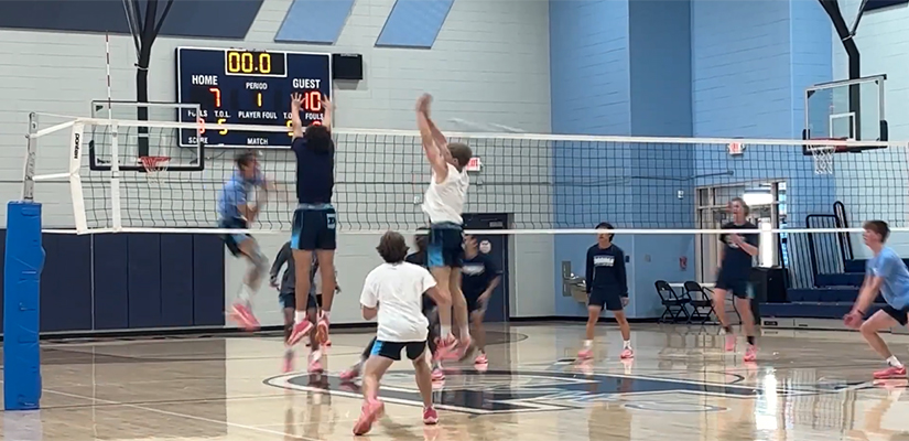 boys playing volleyball inside in a gym
