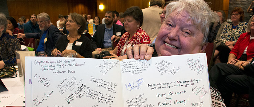 Friends and colleagues signed a copy of "Where the Wild Things Are" for the retiring Dr. Pat. Pat is holding the book.