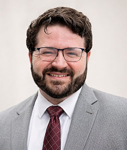 Chase Bailey, wearing a gray siut and a red tie.