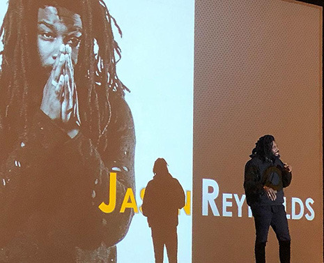 Jason Reynolds on stage in front of a screen showing his name and photo